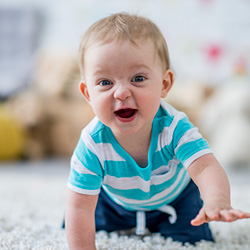 A baby in a turquoise striped shirt crawling