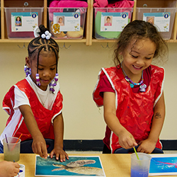 Two girls doing an art activity at the table in a classroom