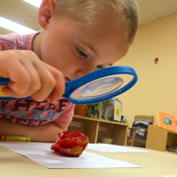 A child using a magnifying glass at a preschool table